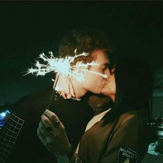 a woman kissing a man holding a sparkler in her hand while he is wearing a police uniform