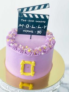 a purple cake with a clapper board on top