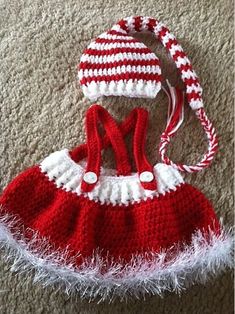 a crocheted red and white dress with matching hat is laying on the floor