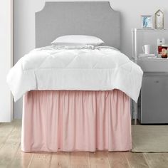 a white bed with pink ruffled bedskirt