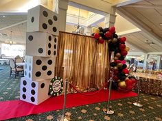 a red carpeted floor with black and white dices on it, surrounded by balloons