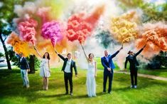 a group of people standing on top of a lush green field covered in colored powder