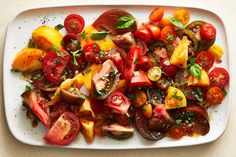 a white plate topped with lots of different types of tomatoes and other veggies