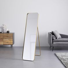 a large mirror sitting on top of a floor next to a couch