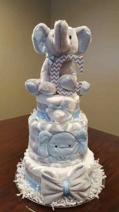 a three tiered diaper cake with an elephant on the top and elephants on the bottom