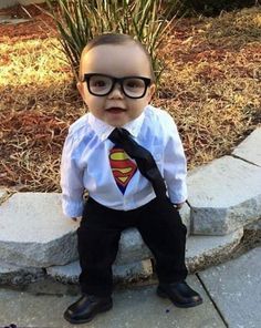 a little boy dressed up in a superman shirt and tie