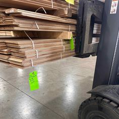 several stacks of wood in a warehouse with green tags hanging from the back of it