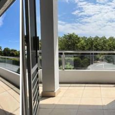 an open balcony with sliding glass doors leading to a parking lot and trees in the background