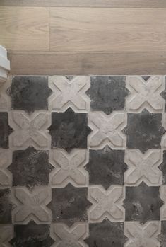 a white toilet sitting in a bathroom next to a tiled wall and wooden flooring