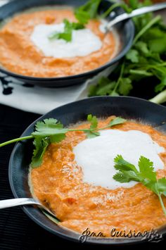 two black bowls filled with soup and garnished with cilantro