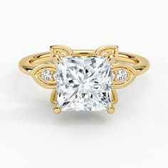 a yellow gold ring with a princess cut diamond in the center and side stones on each band