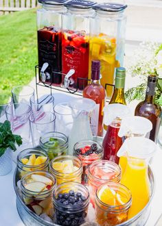 a table topped with jars filled with different types of drinks and fruit on top of it