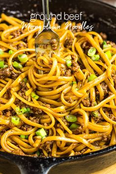 a skillet filled with noodles and ground beef being stirred by a ladle in it