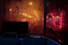 two seats are sitting in front of a window on a rainy night with street lights