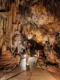 a woman walking through a cave filled with lots of stalate and rock formations