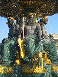 the fountain has statues on it and is surrounded by water splashing from its sides