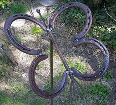 an iron sculpture in the middle of some grass and dirt with vines growing out of it