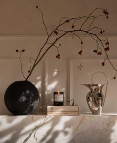 a vase sitting on top of a white counter next to a candle and some books