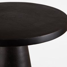 a round table with black top sitting on a white surface