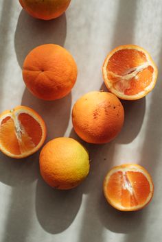 five oranges cut in half sitting on a white table cloth next to each other