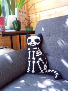 a knitted toy sitting on top of a blue couch next to a potted plant