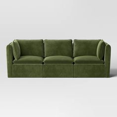 a green velvet sofa with four seats and one arm folded back to the side, on a white background