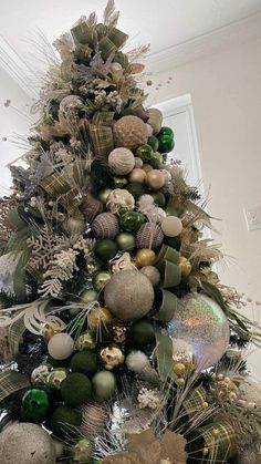 a christmas tree decorated with ornaments and greenery in silver, gold and green colors