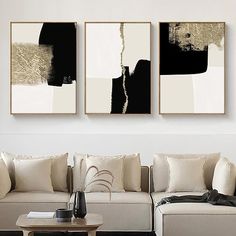 three black and white paintings hanging on the wall above a couch in a living room