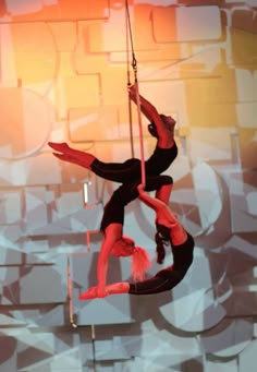 two acrobatic performers performing aerial acrobatics in front of an abstract background