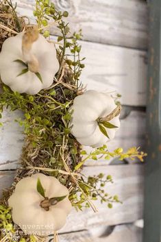 some white pumpkins are hanging from a wreath