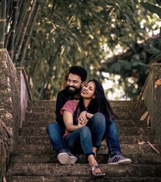 a man and woman are sitting on the steps together smiling at each other as they hug