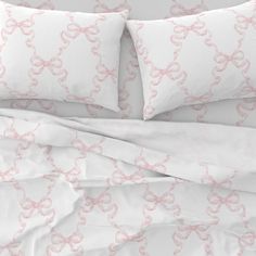 a bed with white sheets and pink bows on it