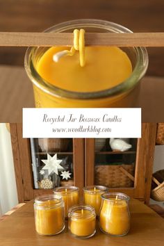 three jars filled with yellow candles sitting on top of a wooden table