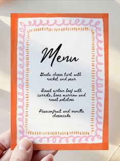 a person holding up a menu card with an orange border around the bottom and black lettering on it