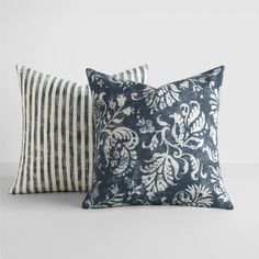 two blue and white pillows sitting next to each other