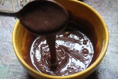 a yellow bowl filled with chocolate pudding and a wooden spoon