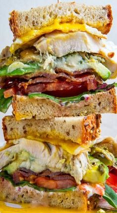 a stack of sandwiches with bacon, lettuce and cheese on them sitting on top of each other