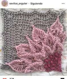 the crocheted flower is on top of the knitted square, which has been stitched together