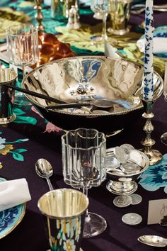 a table topped with lots of silverware and plates on top of a purple table cloth