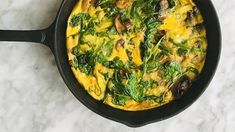 an omelet with spinach and mushrooms in a skillet on a marble counter