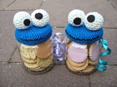 two jars with cookies in them are decorated like cookie monster eyes and one is wearing a blue knitted hat