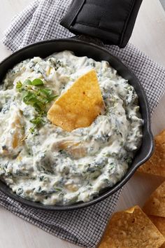 a skillet filled with dip and tortilla chips on top of a table