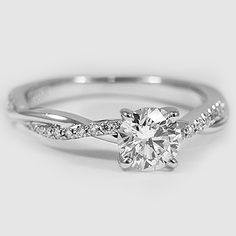 a white gold engagement ring with a twisted band and a round diamond in the center