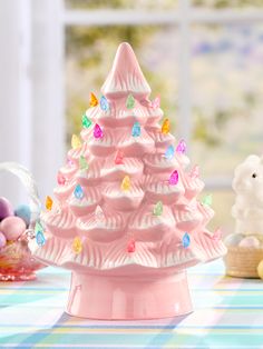 a pink ceramic christmas tree sitting on top of a table next to other toys and decorations