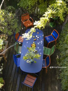 an overhead view of a table and chairs on a wooden deck surrounded by greenery