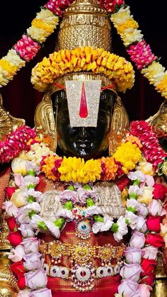 the statue is adorned with flowers and garlands on it's head, surrounded by other decorations