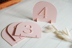 two pink wooden numbers on a white table