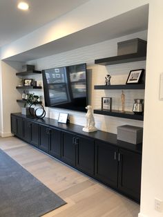 a large entertainment center with black cabinets and shelves on the wall, along with a gray rug