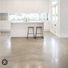 two stools are in the middle of a kitchen with white cabinets and countertops