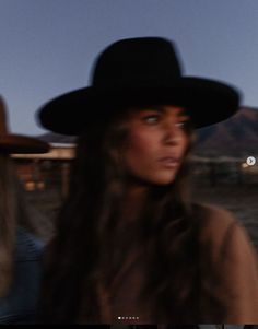 a woman wearing a black cowboy hat in the desert